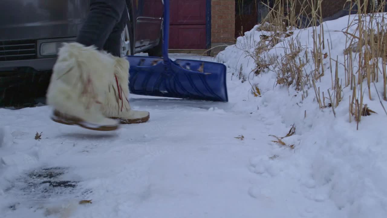 Unas botas de piel y una pala trabajando para quitar la nieve de una entrada de vehículos.