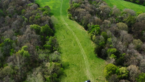 car of land surveyor parked on the green meadow during property survey in siloam springs, arkansas, usa - aerial shot