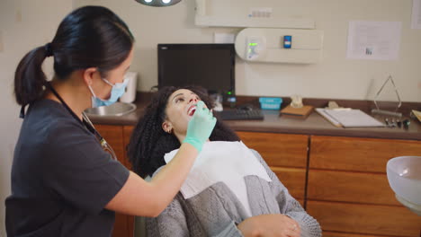 Dentist-talking-to-a-female-patient-while-checking