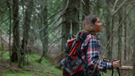 woman with trekking poles hiking in forest