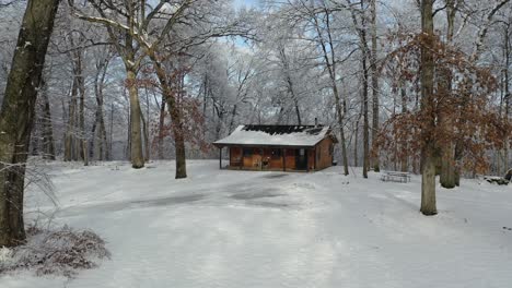 Snowfall-With-View-of-Entrance-of-Wooden-Cabin,-Backwards-High-Dolly