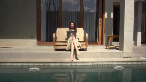 Business-expat-woman-working-online-in-her-luxury-home-with-swimming-pool-in-Bali,-Indonesia