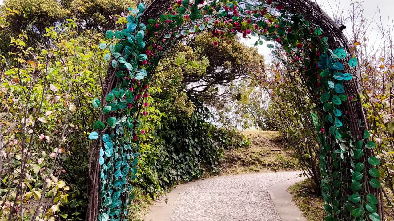 Decorative arch, lush leaves, flowers welcomes visitors on winding garden trail