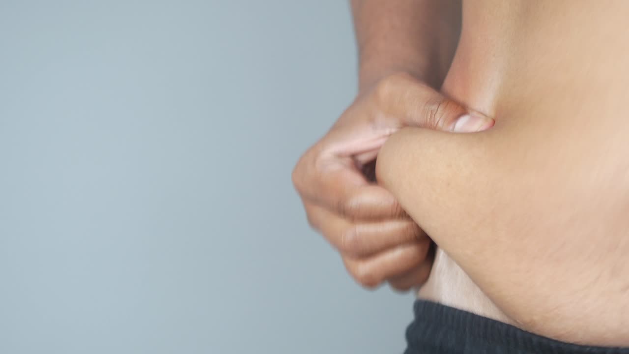 cerca de la mano de un hombre sosteniendo su grasa estomacal