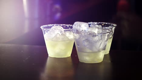 el cantinero vierte el último trozo de mezcla de maragarita en vasos de plástico forrados con sal