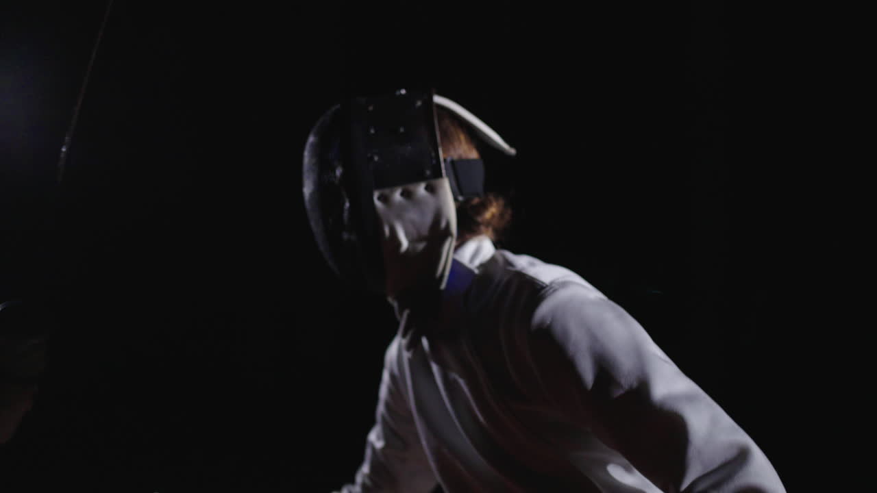 dos mujeres esgrimistas compiten en un entorno oscuro.