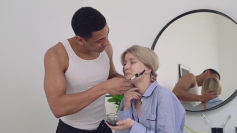 apuesto hombre negro aplicando máscara facial a una mujer