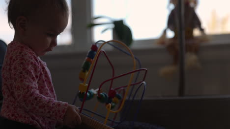 1 year old girl plays with her toy set in living room - side profile