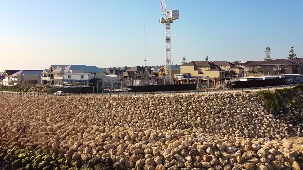 Rocky sea wall and waterfront homes at Claytons Residences in Mindarie, Australia on a sunny day