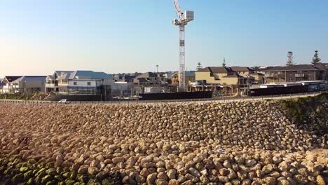 rocky sea wall and waterfront homes at claytons residences in mindarie, australia on a sunny day