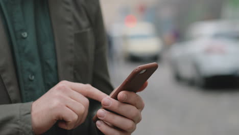 close-up view of caucasian man hands typing and texting on the smartphone in the street in autumn, then the camera focuses on his smiled face