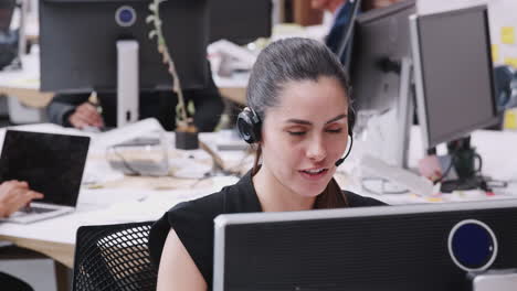 female customer services agent working at desk in call center