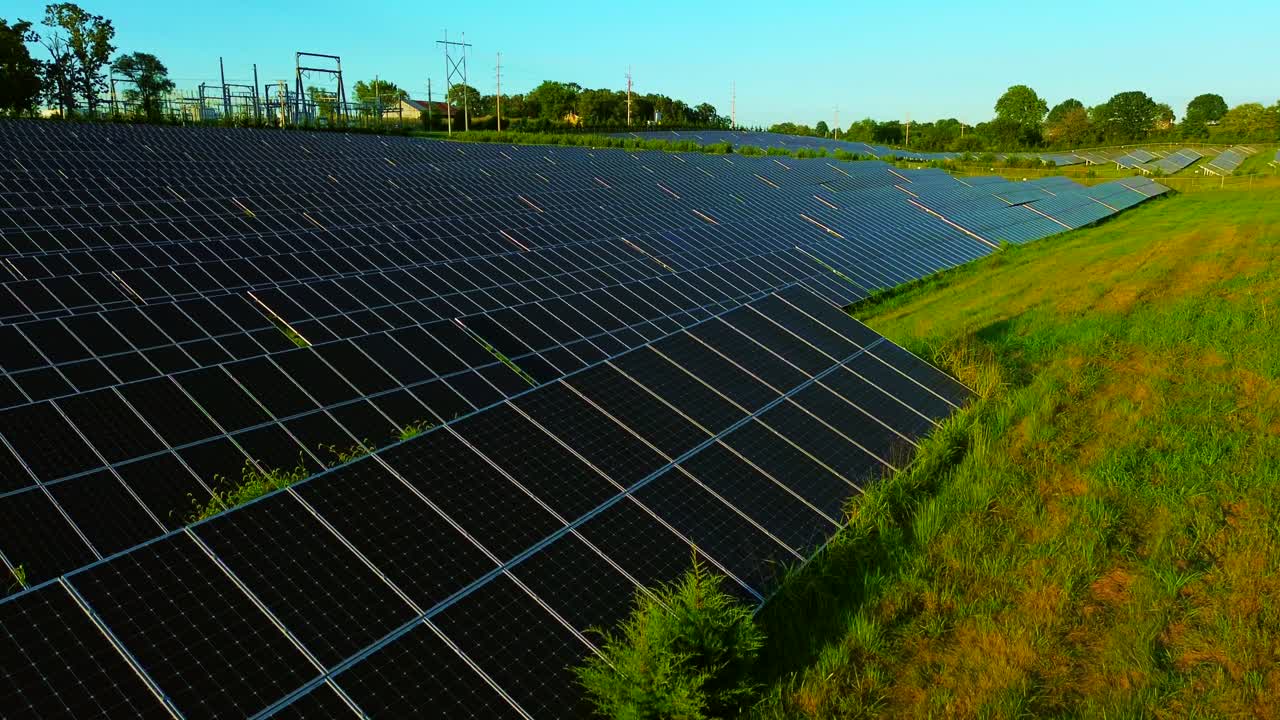 Low altitude drone flyover approaching rows of solar panels at a solar farm in Nixa Missouri during golden hour in cinematic 4K HD footage