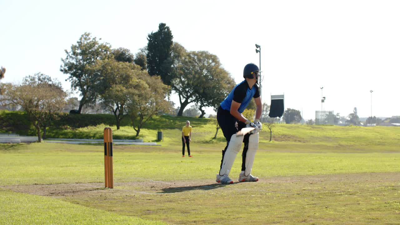 Cricket player walking on field holding bat, enjoying sunny day outdoors
