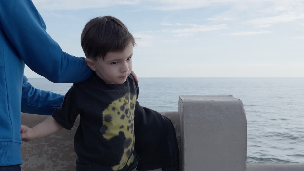 A woman helps undress a toddler boy near the seafront