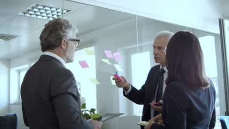 company leaders writing and sticking papers on wall