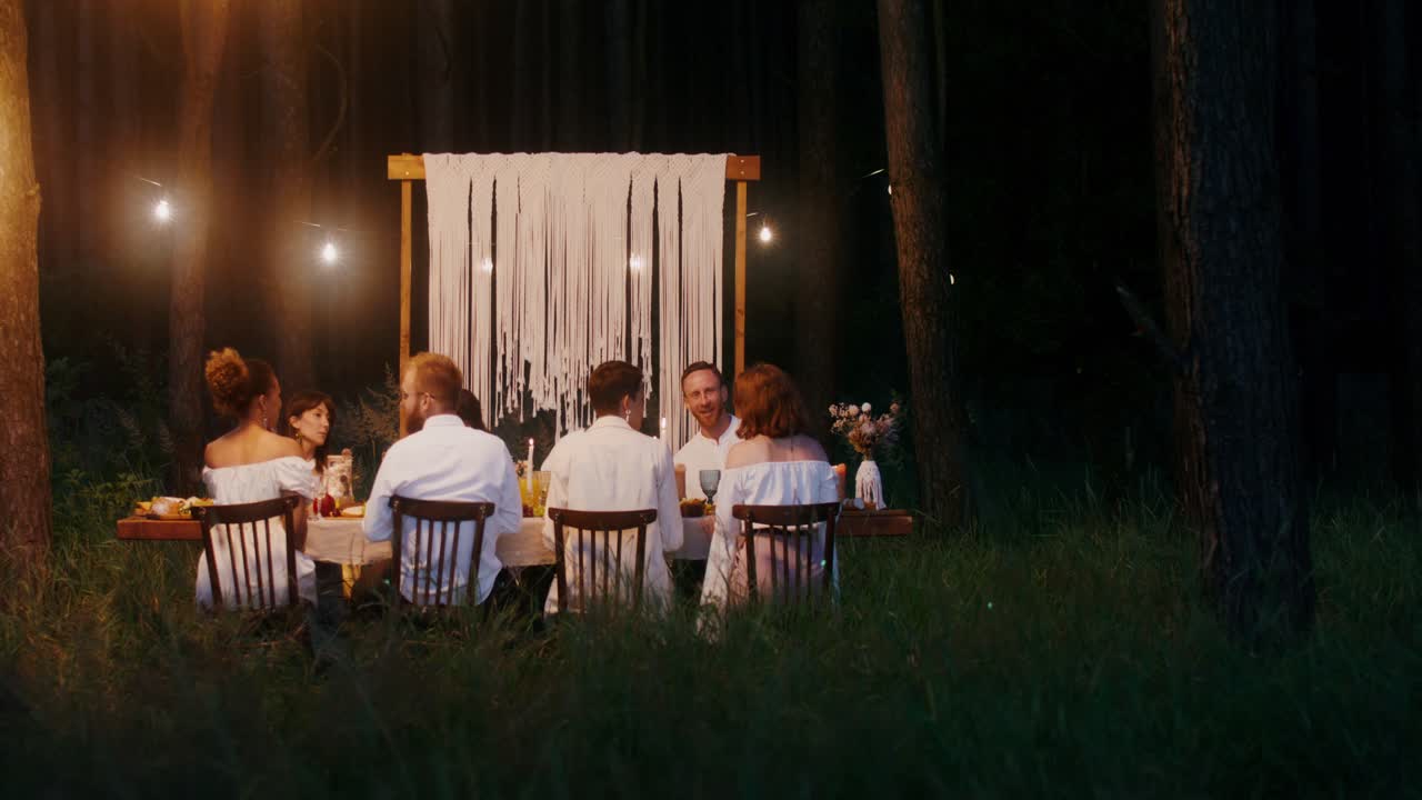 Amici che cenano all'aperto nel bosco di notte