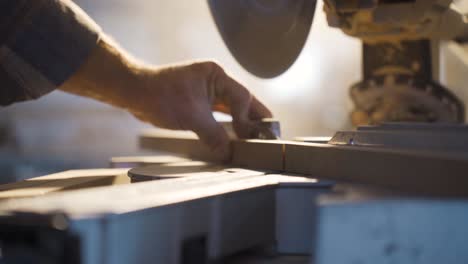 male carpenter cuts wood with circular saw in carpentry workshop.