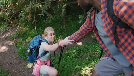 Happy-diverse-couple-hiking-with-backpacks-in-park,-slow-motion