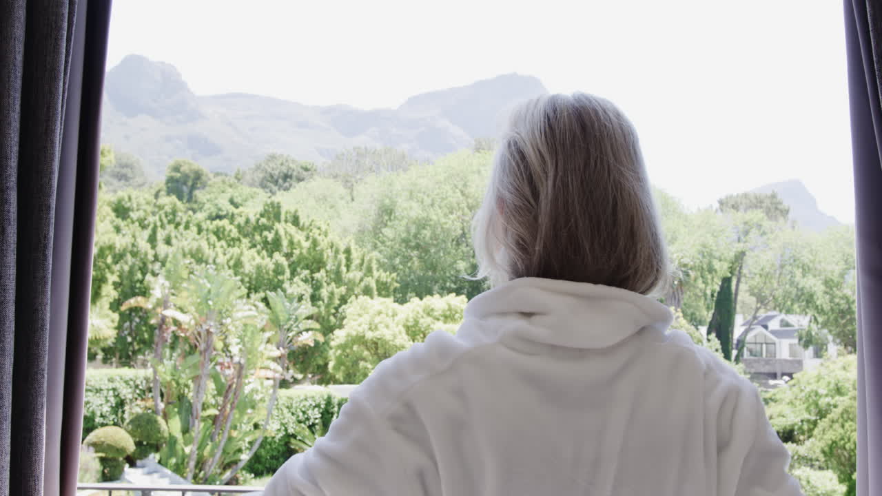 Senior woman enjoying peaceful mountain view from balcony, embracing tranquility, copy space