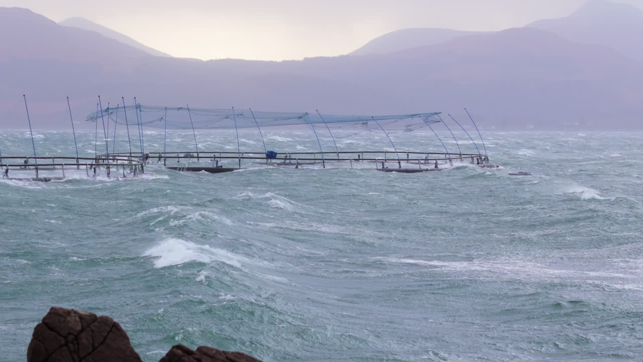 Salmon farm fish pens battered by choppy waters on Sound of Mull, UK aquaculture
