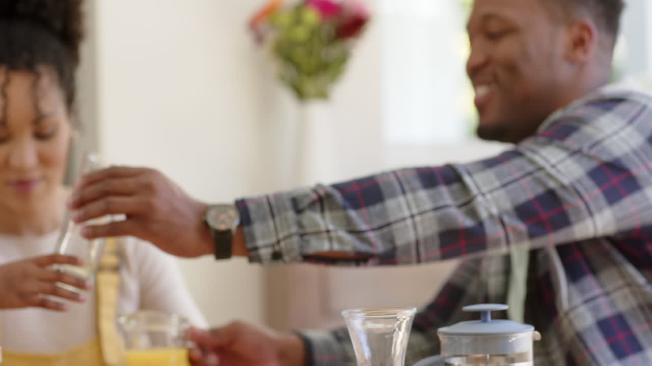 felices padres afroamericanos y su hija desayunando en casa, en cámara lenta.