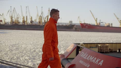 Dockarbeiter-In-Orangefarbener-Uniform,-Der-Im-Hafen-Spazieren-Geht-Und-Den-Arbeitsprozess-Im-Hafen-Kontrolliert.-Vereistes-Meer