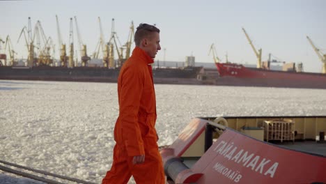 Dock-worker-in-orange-uniform-walking-in-the-harbor-and-controlling-working-process-in-the-port.-Iced-sea