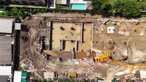 aerial view of a residential construction site with foundation work, workers, and crane