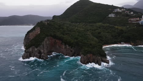 Aerial-drone-shot-over-the-scenic-cliffs-and-lush-green-vegetation-over-the-mountainous-terrain-with-Adriatic-sea-below-in-Montenegro-on-a-cloudy-day