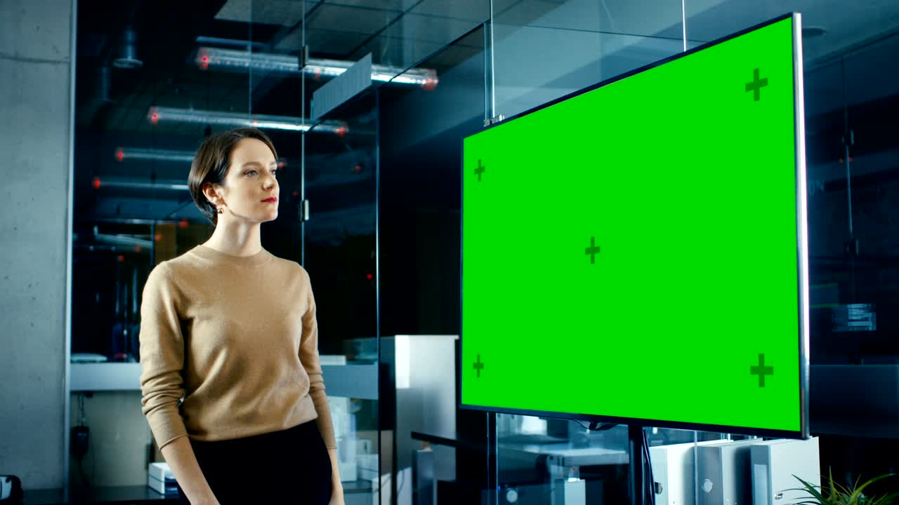 늦은 밤에 아름다운 백인 여성은 회의실에서 모형 크로마 키 녹색 스크린 tv를보고 있습니다.