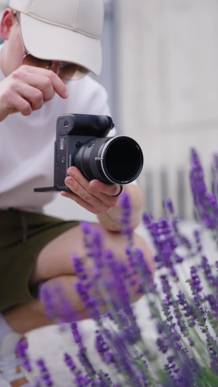 Plano vertical de fotógrafo testando filtro ND variável perto de arbusto de lavanda.