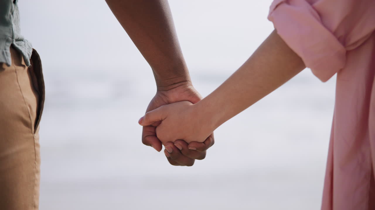 Interracial couple holding hands on the beach