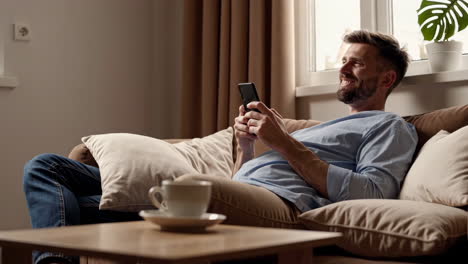 man relaxing on a couch using his smartphone