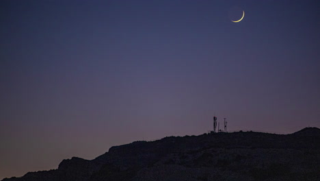 timelapse of the crescent moon in motion at night over a mountain