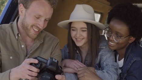 un joven fotógrafo muestra las fotografías que ha tomado a dos hermosas jóvenes dentro de la caravana durante un viaje por carretera 4