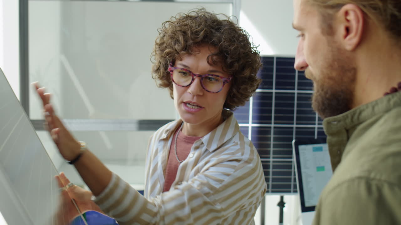 Female Renewable Energy Developer Discussing Solar Panel with Coworker