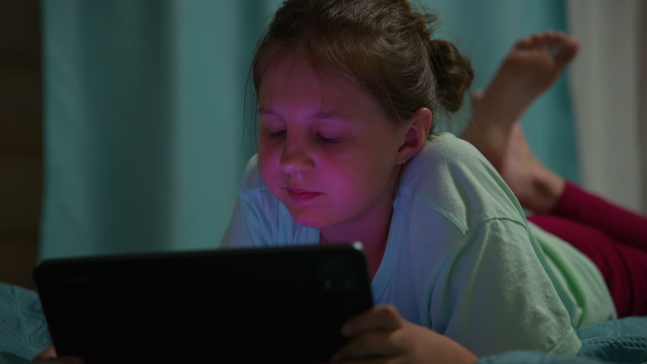 Young Girl Lying on Bed Watching Tablet Screen