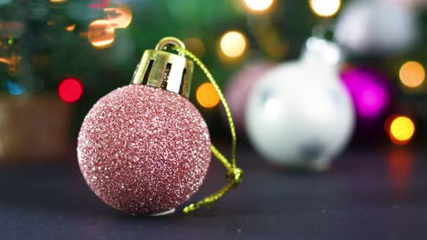 luces de navidad parpadeantes y un pequeño brillo rosa pastel adorno de árbol de navidad en la mesa