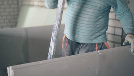 man-holds-large-ruler-and-measures-gypsum-plasterboard