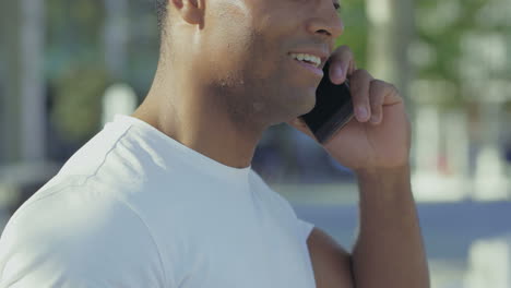 side view of smiling guy talking on smartphone.