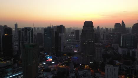 drone descending above skyline and skyscrapers of sukhumvit district during colorful red sunrise in bangkok, thailand