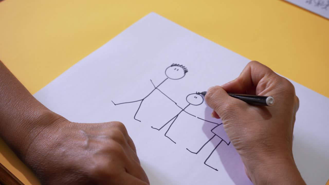 Crop View Of Person Drawing Stick Figures Of A Family On White Bond Paper