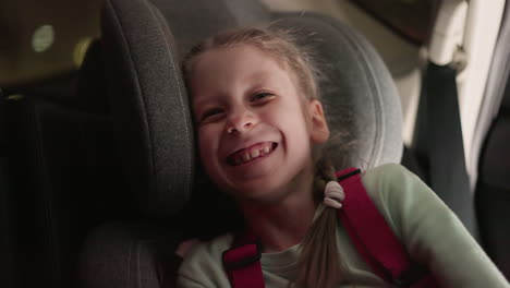 a close view of a child laughing joyfully while seated in a car, the child's expression of pure happiness is captured beautifully, with blurred lights seen through the car window