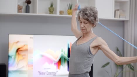 senior woman doing resistance band arm exercises at home