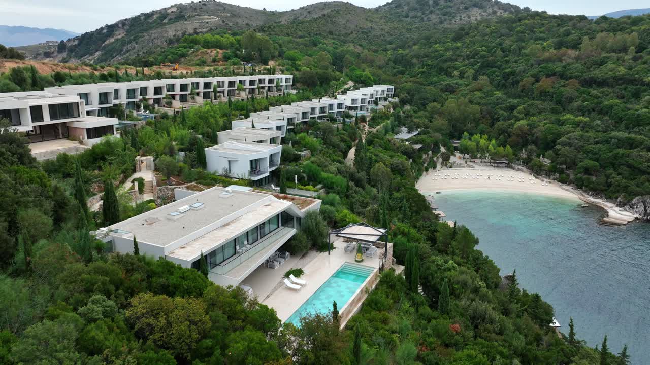 Resort coastline in Saranda, Albania with hotels and pool beside turquoise Ionian Sea