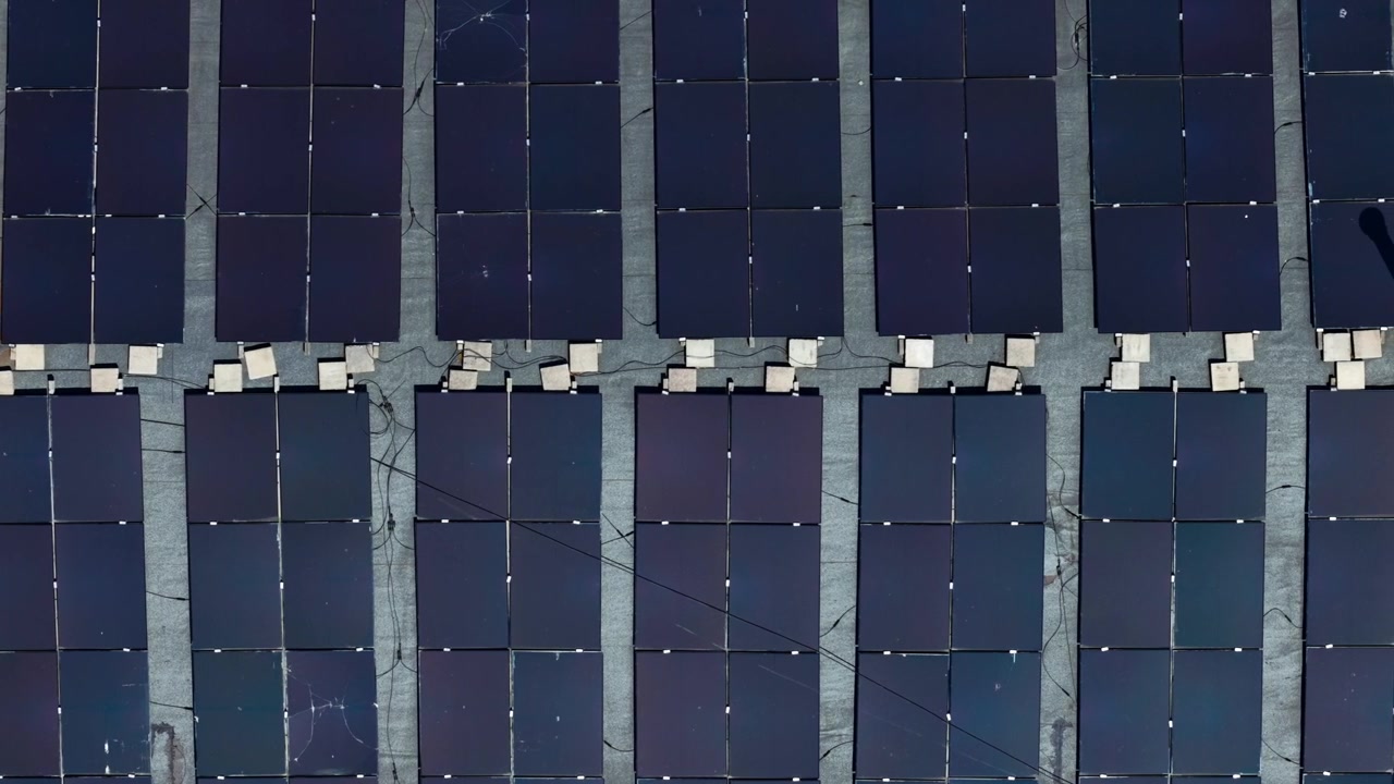 Vista dall'alto con drone di pannelli solari sui tetti che formano puliti motivi geometrici.