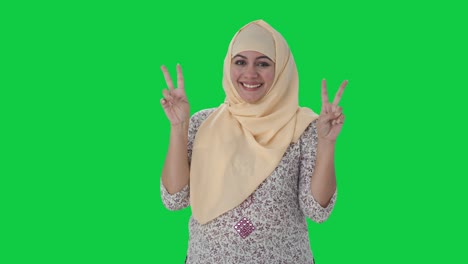 happy muslim teacher showing victory sign green screen