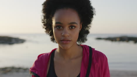 Porträt-Einer-Jungen-Afroamerikanischen-Frau,-Die-Mit-Wunderschönen,-Verträumten-Augen-Am-Ruhigen-Strand-Am-Meer-In-Die-Kamera-Blickt