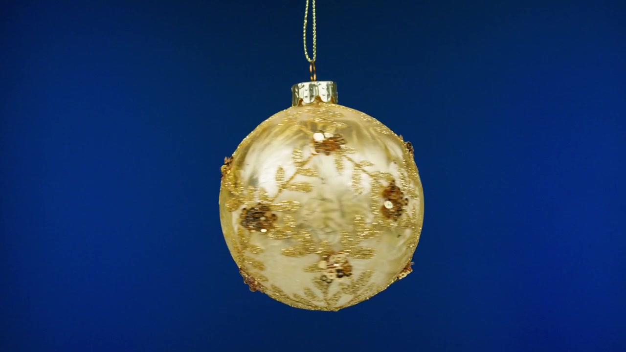 Goldene glitzernde Weihnachtskugel rotiert auf blauem Hintergrund